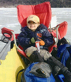 My little boy hops a ride across the ice behind the ATV