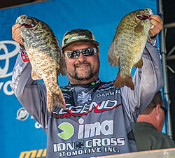 Bassmaster Elite Pro Fred Roumbanis holding up two smallmouths caught on an Optimum swimbaits.