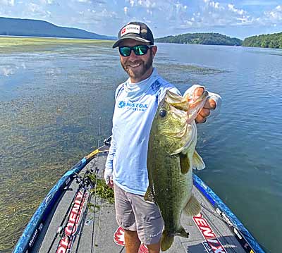 Brandon Lester with a bass caught from thick vegetation.