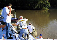 Tony Stewart, via cell phone, tells good friend Johnny Morris, founder of Bass Pro Shops, about the fish as they go into the lake. To Tony's right is his dad, Nelson.