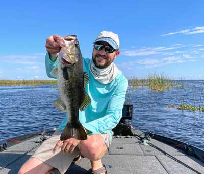 The author with an Okeechobee bass caught with a swim jig around scattered reeds and eelgrass.