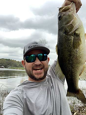 The author, with a nice bass, caught from the shoreline adjacent to a busy boat ramp.