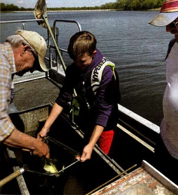 Greg Graves measures a fish with his grandson, Deuce Chanos, as son-in-law Jason Chanos looks on.