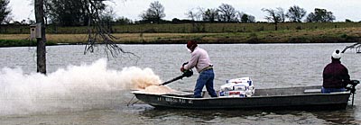 A landowner applying powdered gypsum to help increase clarity in his pond.