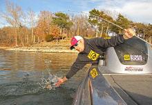 Local angler Mitch Webb reaches far to prevent a bass he hooked near the mouth of Drowning Creek from getting away.